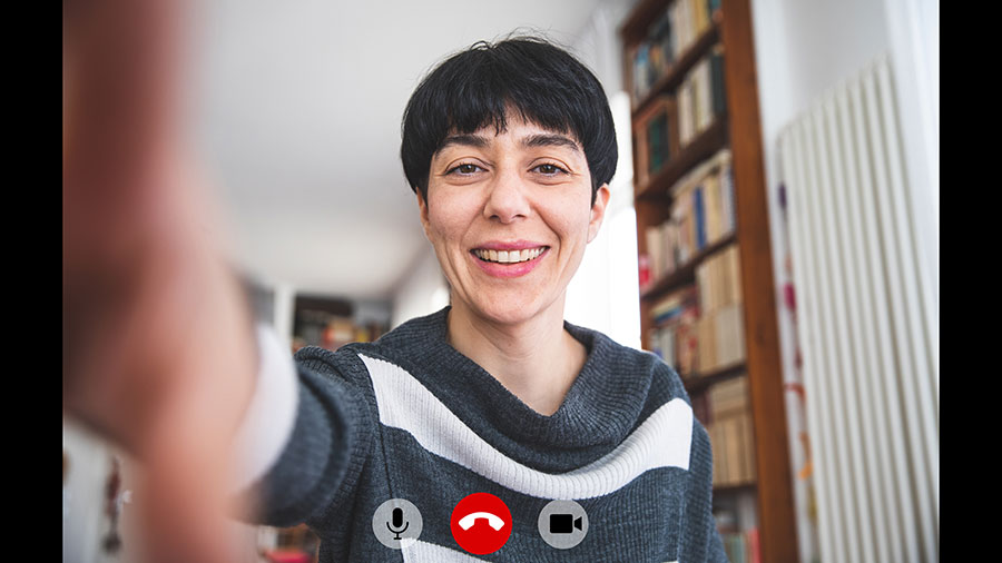 Una imagen de una mujer que sonríe aparece en una computadora portátil. Los íconos de audio, video y teléfono aparecen en la parte inferior.