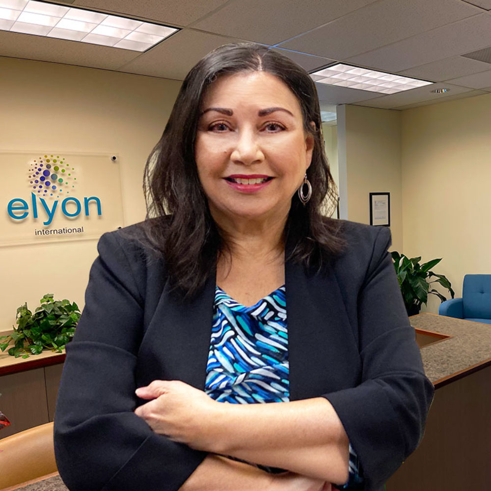 Carmen Nazario aparece en la sede de ELYON International en Vancouver, Washington. El logotipo de ELYON International aparece sobre su hombro derecho.