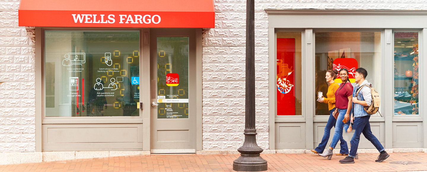 Three people walk past a Wells Fargo branch.