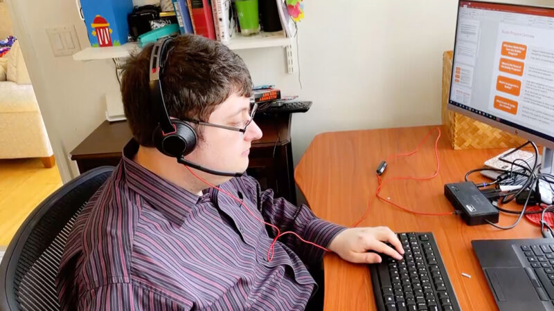Alex Lieberman, wearing a headset sitting at computer