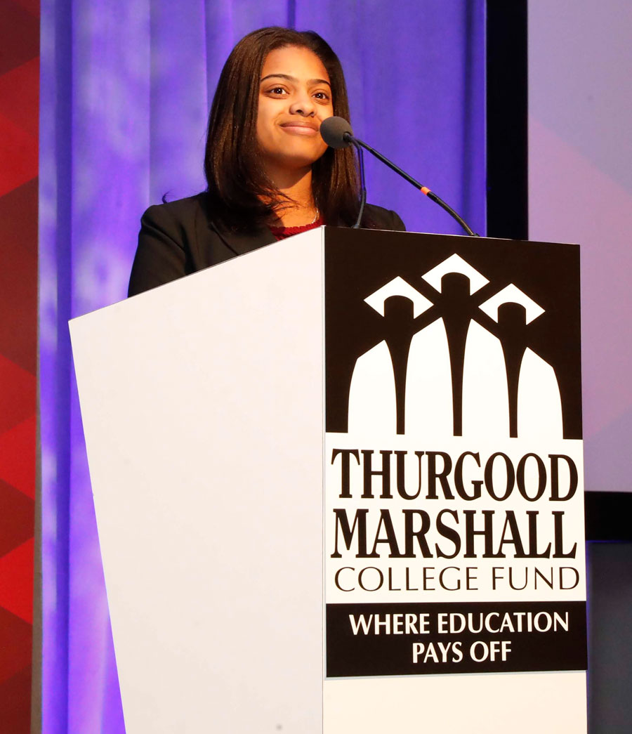 A woman stands at a podium that says Thurgood Marshall College Fund. Where education pays off.