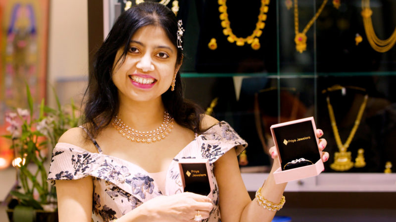 Priya Vasan holds up two jewelry boxes containing gold bracelets