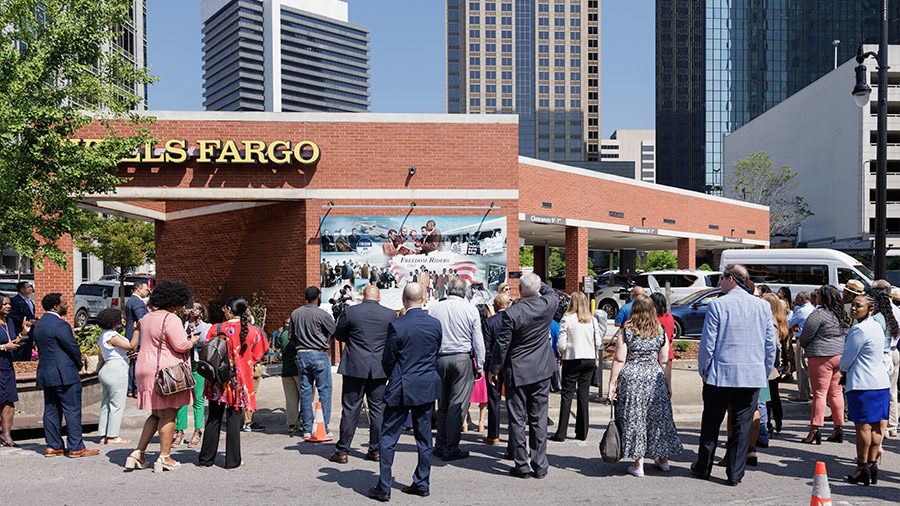 A large crowd stands in front of the Freedom Riders mural at a Wells Fargo branch in Birmingham, Alabama.