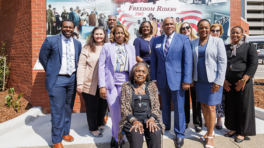 A group of individuals in front of the Freedom Riders mural.
