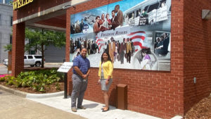 Alex Gay and Monique Henderson stand in front of the Wells Fargo mural honoring the Freedom Riders.
