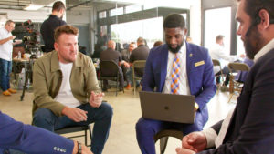 Four men sit on chairs in a circle discussing opportunities for veteran small business owners.