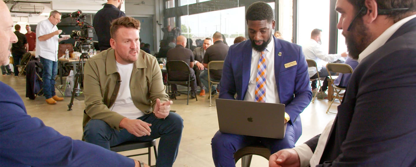 Four men sit on chairs in a circle discussing opportunities for veteran small business owners.