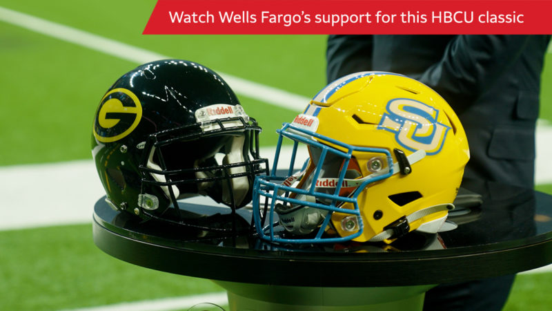Grambling State and Southern University football helmets sit on a table facing each other. Above them, white letters across a red bar read “Watch Wells Fargo’s support for this HBCU classic.”