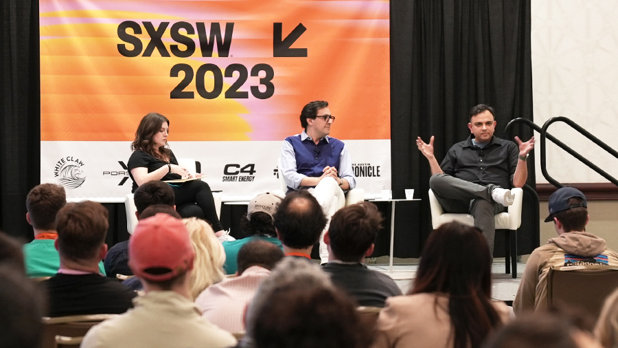 Three speakers are seated on the SXSW 2023 stage addressing an audience.