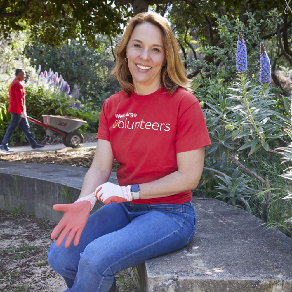 Wells Fargo’s first Chief Sustainability Officer Robyn Luhning sits outside wearing a red Wells Fargo Volunteers t-shirt.