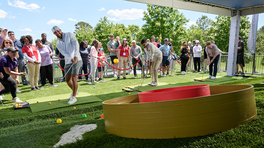 Several people stand around a golf challenge game.