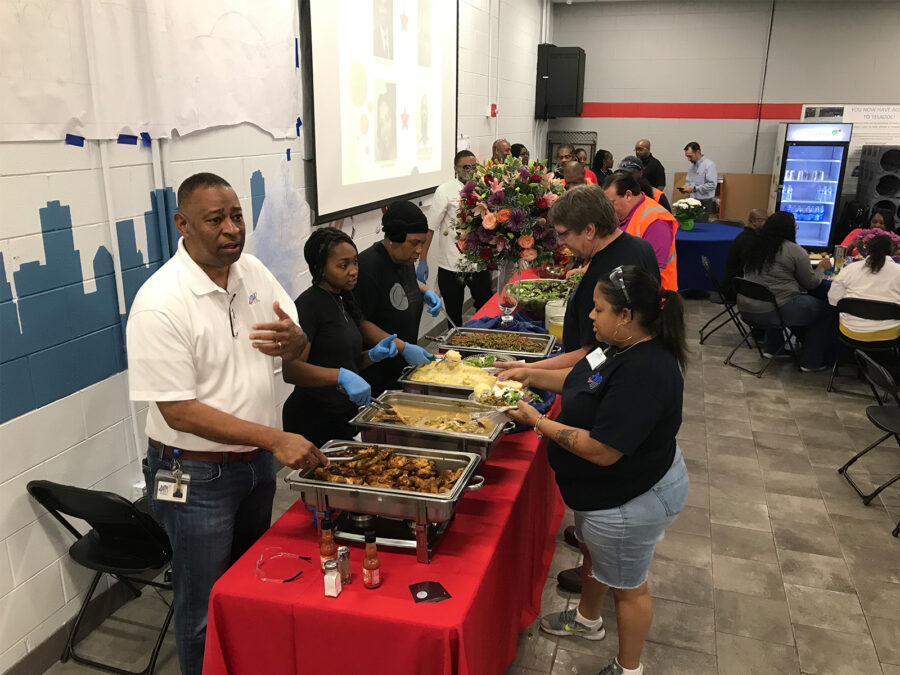 A buffet of food is set up in an office building and people are serving the food to others.