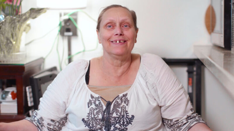 Karrie, a resident of Orchid, a permanent supportive housing project in Los Angeles, sits in her fully furnished apartment, which is a converted hotel room.