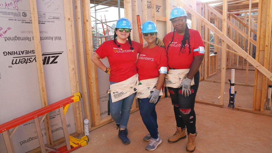 Three women take a break from working and pose in an unfinished home.