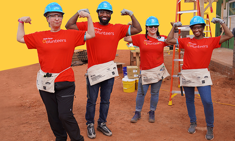 Four people in construction hats and red volunteer shirts pose for a photo.