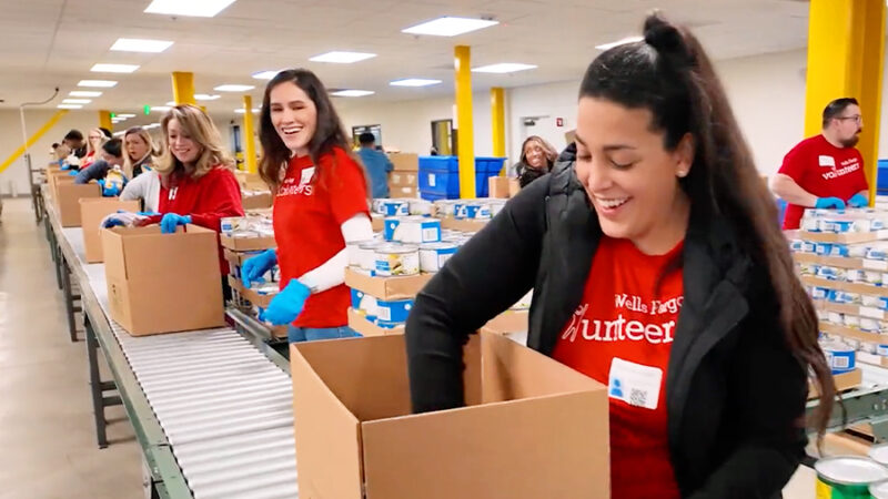 People stand alongside a conveyor belt as they load supplies into donation boxes.