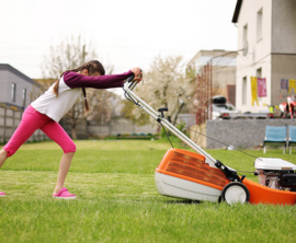 A teen pushes a lawn mower over a lawn of green grass.