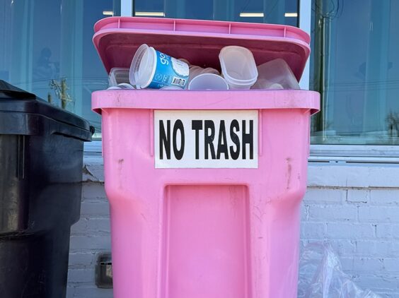 A pink garbage can with the label No Trash is full of plastic