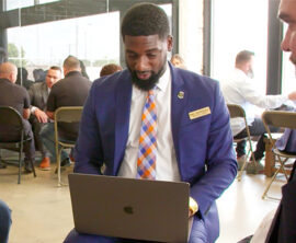 In a large open room, groups of four are gathered in discussion circles.