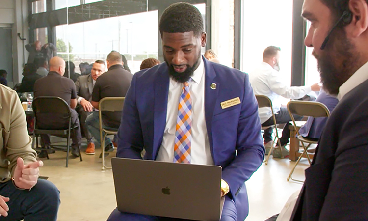 In a large open room, groups of four are gathered in discussion circles.