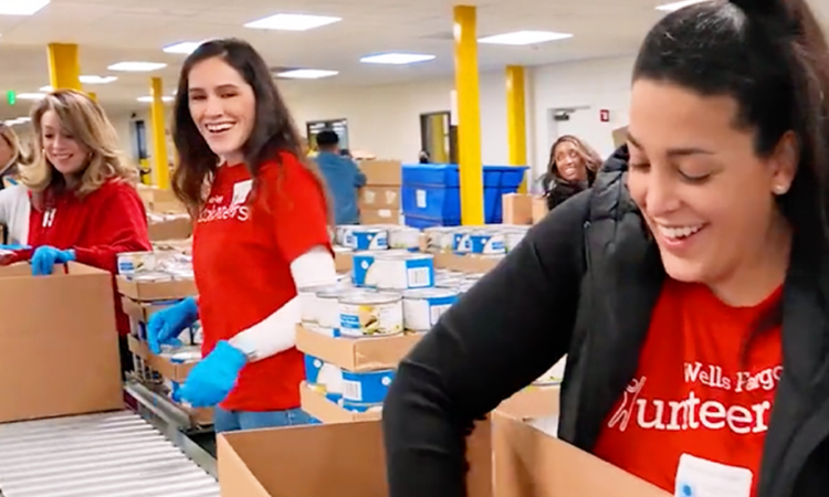 People stand alongside a conveyor belt as they load supplies into donation boxes.