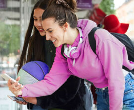 Two students smile as they look at a smartphone