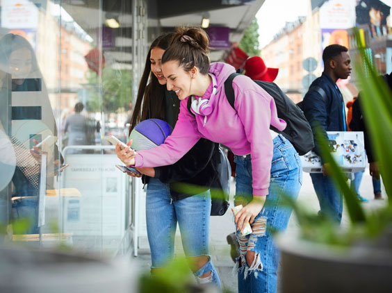 Two students smile as they look at a smartphone
