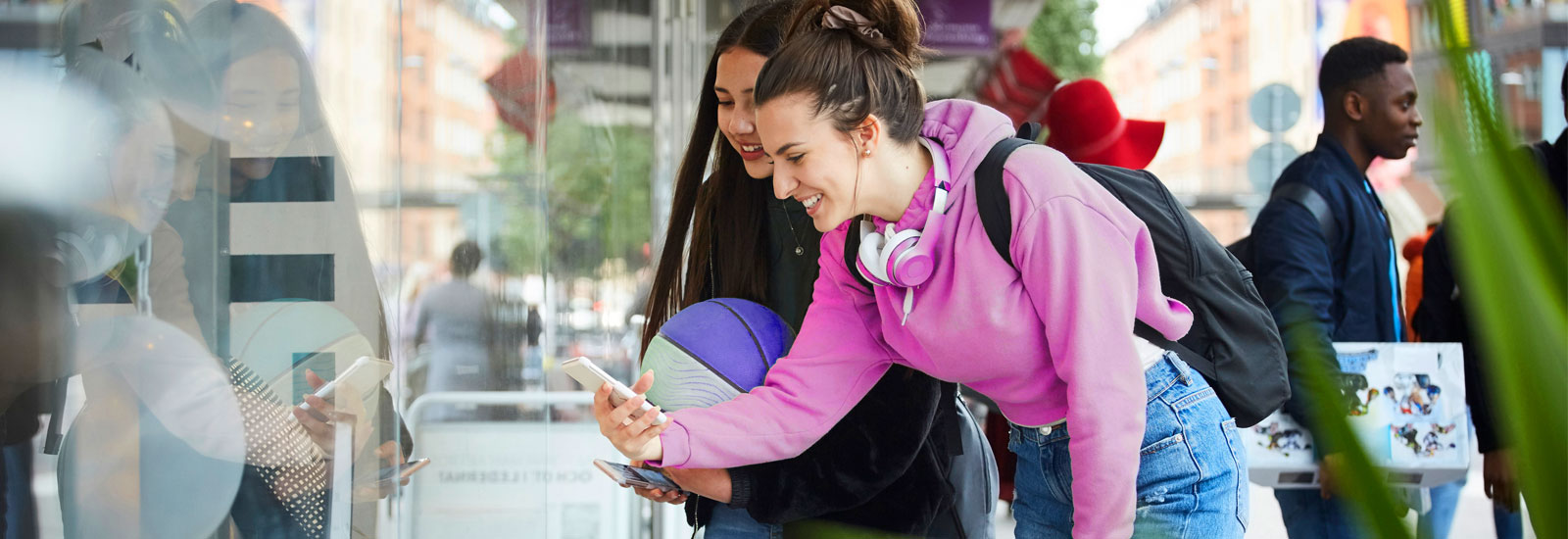 Two students smile as they look at a smartphone