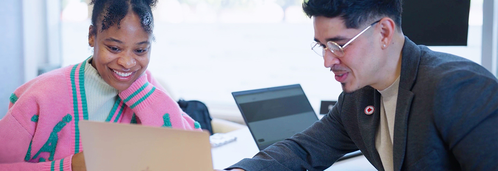 A woman and a man look at a laptop screen