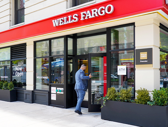 A man in a blue suit is walking into a Wells Fargo branch.
