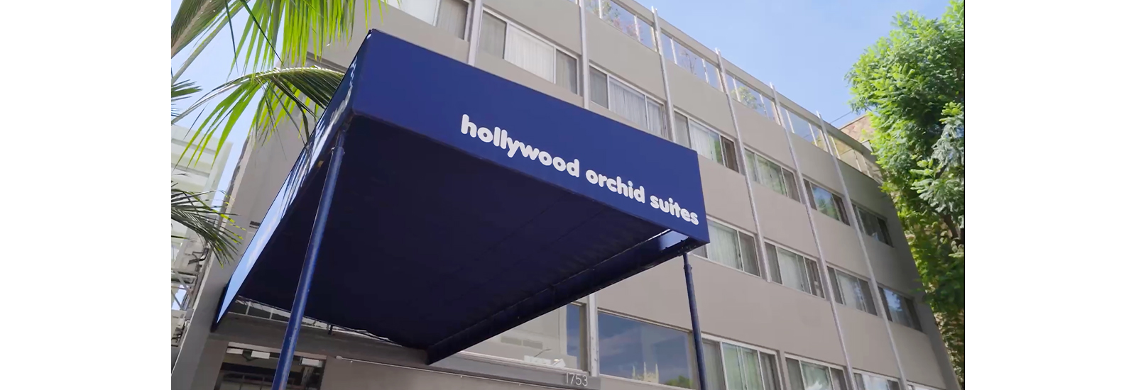 A building is shown with a blue canopy that reads hollywood orchid suites