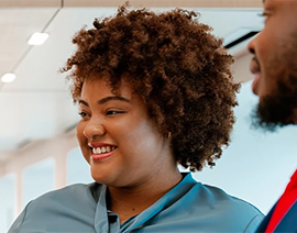 A women in a blue shirt is shown looking to the side and smiling.