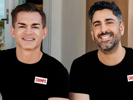 Two men in black shirts with the CHOMPS logo are smiling at the camera.