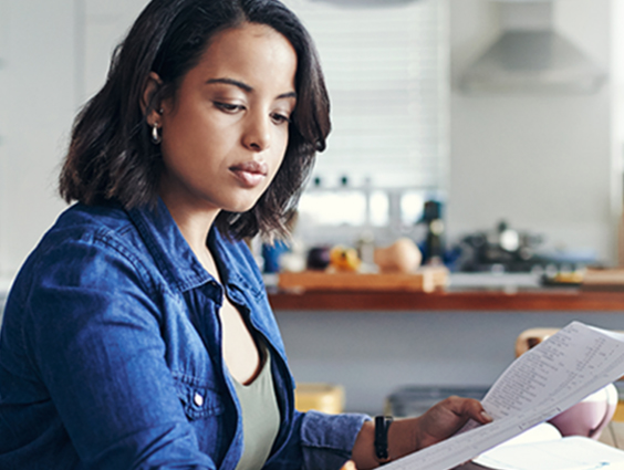 A woman looks over as sheet of paper as she pays her taxes.