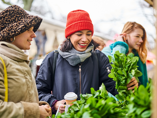 Three women bundled in winter gear are outside shopping.