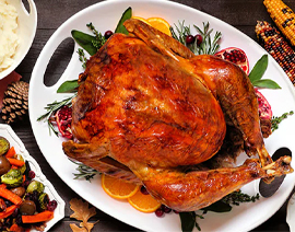 A cooked Thanksgiving turkey is on a platter with veggies around it.