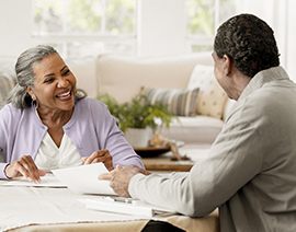 A man and woman smile at each other as they look at their year end spending spreadsheets.