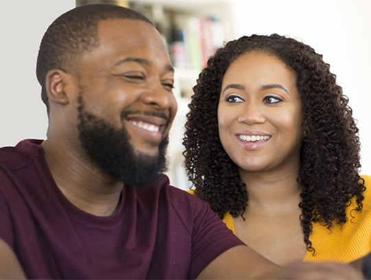 A couple laughs together while discussing refinancing their home.