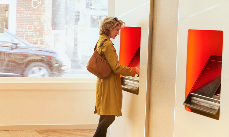 A woman stands at an ATM