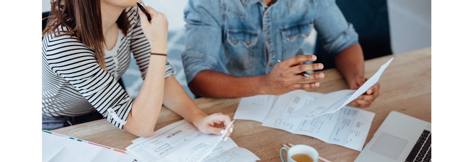 A couple sits at a table reviewing financial documents.