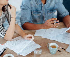 A couple sits at a table reviewing financial documents.