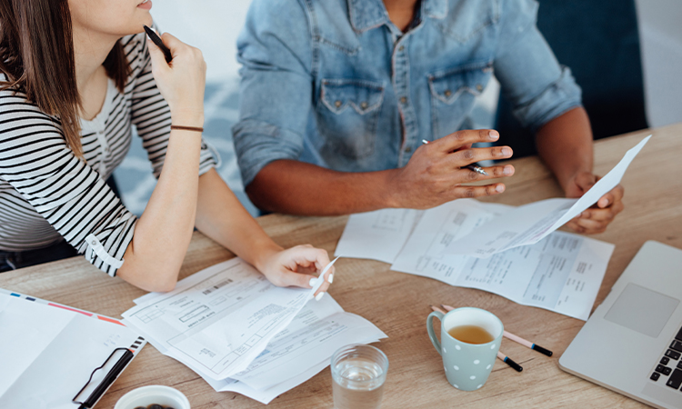 A couple sits at a table reviewing financial documents.