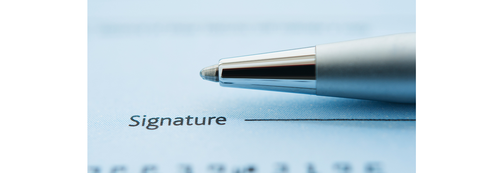 A ballpoint pen rests on a piece of paper above the word Signature