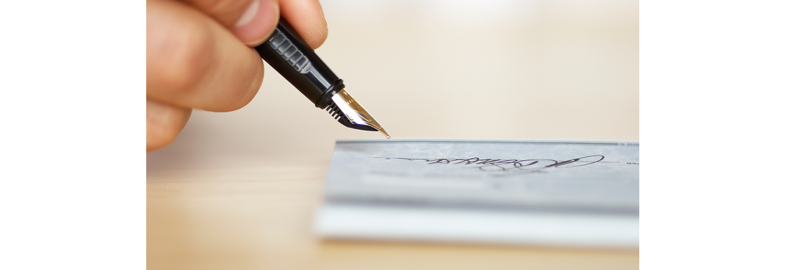 A hand holds a pen while signing a document