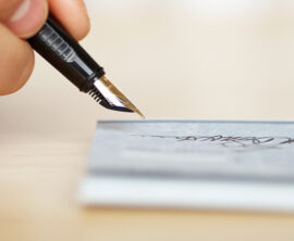 A hand holds a pen while signing a document