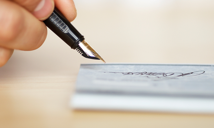 A hand holds a pen while signing a document