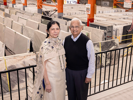 A man and woman stand together smiling