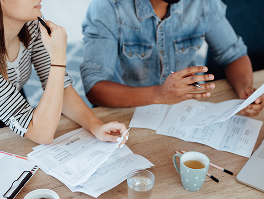 A couple sits at a table reviewing financial documents.