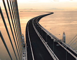 A bridge winds overs a body of water. Support beams are seen on the sides.