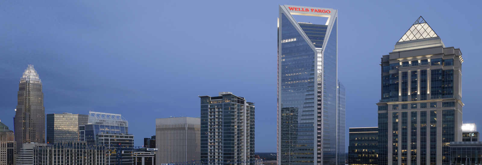 A nighttime skyline of Charlotte, North Carolina, showing the Wells Fargo signage.